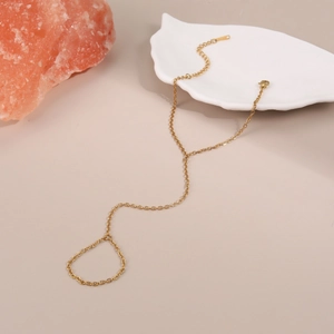 Vista dettagliata di un bracciale da dito dorato con catena sottile e anello abbinato