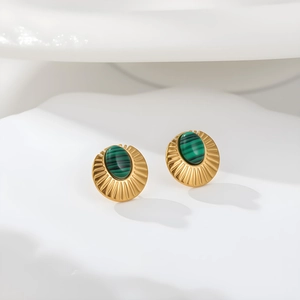 Detalle de pendientes dorados con piedra malaquita verde y diseño de rayos de sol