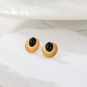 Detalle de pendientes dorados de acero inoxidable con piedra negra y textura solar