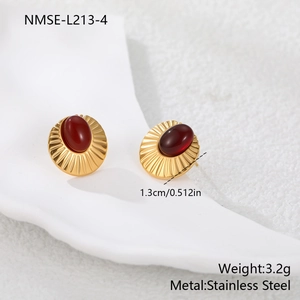 Detalle de pendientes vintage de acero dorado con ágata roja y textura de sol