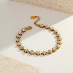 Close-up of gold-plated bracelet with pavé-set round zircon charms and lobster clasp