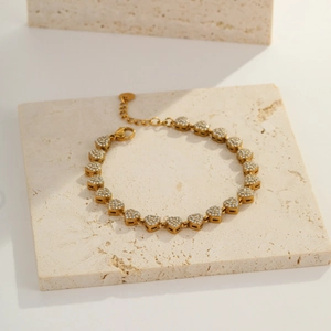 Detail of gold heart link bracelet with white cubic zirconia on textured stone