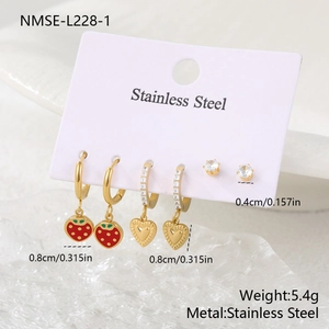 Three pairs of gold stainless steel earrings with strawberry and heart charms on a card
