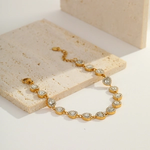 Close-up of gold plated heart link bracelet with white zircon pave on travertine stone