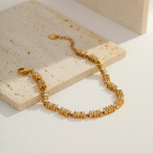 Detailed macro view of a gold-plated bracelet with round cubic zirconia and lobster clasp