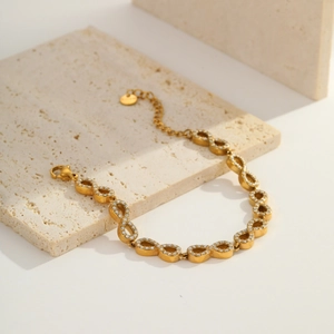 Detailed close-up of golden infinity link bracelet with white zircon and lobster clasp