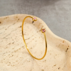 Detail of gold-plated stainless steel open bangle with pink round zircon stones
