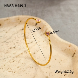Detail view of gold-plated open cuff bracelet with pink zircon stones and size specs