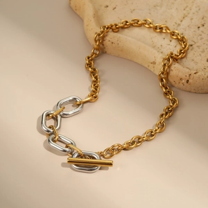 Macro detail of two-tone gold and silver chain necklace with toggle clasp on stone
