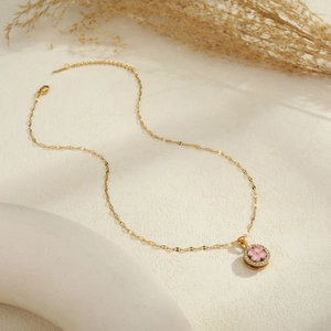 Dettaglio della collana dorata con ciondolo a fiore rosa e zirconi cubici lucidi
