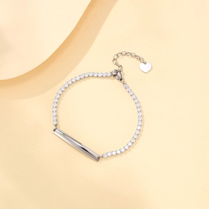 Detalle de pulsera tenis plateada con circonitas y placa de corazón grabable