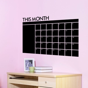 Sticker mural tableau noir avec grille de calendrier mensuel sur un mur rose clair