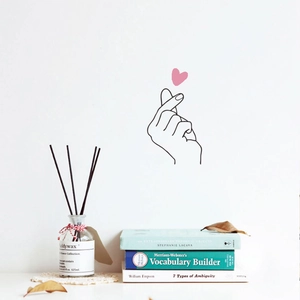 Detail of creative heart gesture wall sticker with pink heart over a white minimalist wall