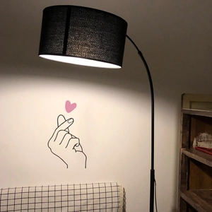 Modern black arc floor lamp with fabric drum shade and heart gesture wall sticker