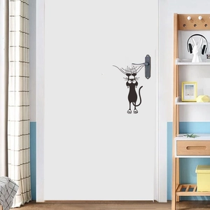 Gros plan d'un autocollant mural chat noir cartoon posé à côté d'une poignée de porte