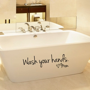 Detail of Wash your hands Mom vinyl wall decal applied on a minimalist bathtub surface