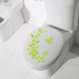 Close-up of green butterfly and floral vine stickers applied on white toilet lid