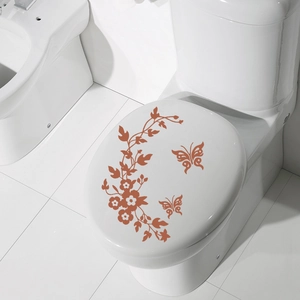 Close-up of brown floral vine and butterfly stickers on a white modern toilet seat
