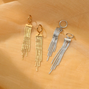 Detail of 18k gold and silver tassel earrings with flat snake chains on silk fabric
