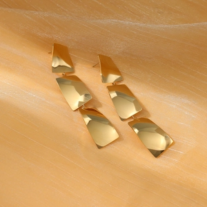 Polished gold geometric fringe earrings with three rectangular drops on orange silk fabric