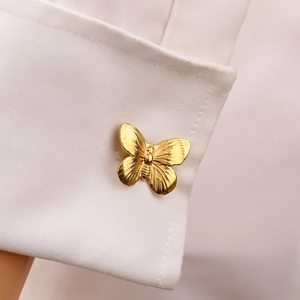 Polished 18K gold butterfly cufflink on a white French shirt cuff sleeve detail