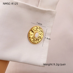 Detailed close-up of oval stainless steel cufflinks with white opal inlay on shirt cuff