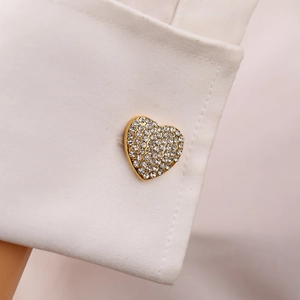 Macro shot of gold heart cufflink with sparkling rhinestones on a white shirt cuff