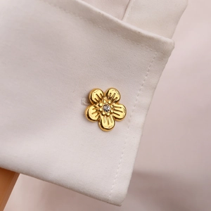 Golden five-petal flower cufflinks with zircon accent on a white formal shirt cuff