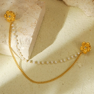 Détail de la broche fleur dorée avec strass, chaîne en métal et perles d'imitation
