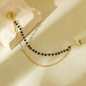 Broche double chaîne dorée et perles noires avec détails cœurs en cristal