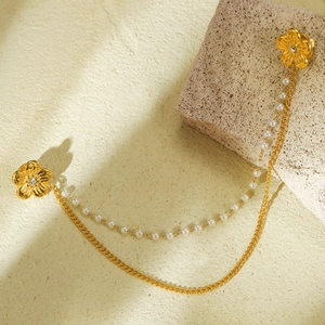 Broche de col fleur dorée avec strass et chaîne de perles sur une surface en pierre