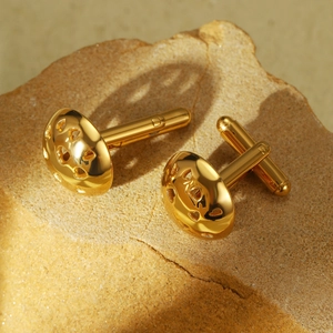 Macro shot of gold cufflinks with heart cutouts on a textured natural stone base