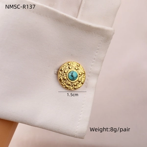 Detail of turquoise cufflinks with hammered gold base on white shirt sleeve
