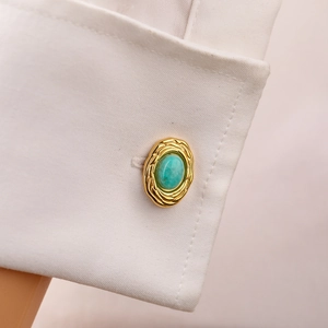 Close-up of vintage turquoise and gold stainless steel cufflink on a white french shirt cuff