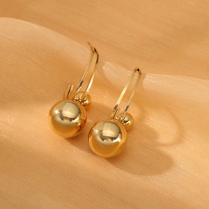 Pendientes de doble bola de acero inoxidable dorado sobre fondo de tela texturizada