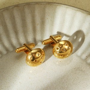 Detailed macro of golden heart cufflinks with cutout design on ceramic plate