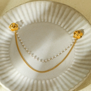 Détail de broches de col fleuries avec chaînes dorées et perles sur céramique