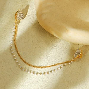 Elegante spilla a cuore dorata con strass e catene di perle su sfondo testurizzato