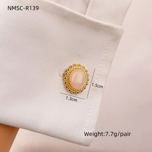 Detail of gold cufflinks with pink turquoise inlay worn on a white shirt sleeve