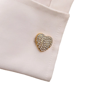 Polished 18K gold heart-shaped cufflink with sparkling zircons on a white shirt sleeve