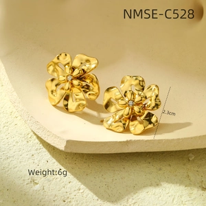 Détail de boucles d'oreilles fleur dorées avec diamant central et texture ondulée