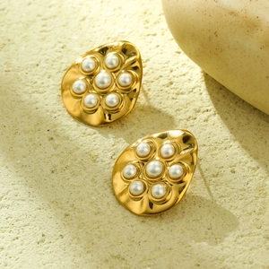 Macro detail of 18K gold irregular hoop earrings with clustered pearls on stone base