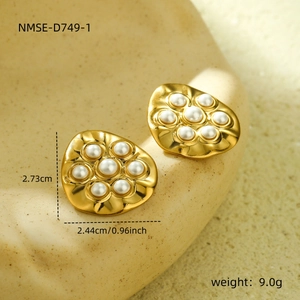 Close-up of vintage 18K gold irregular hammered earrings with inlaid pearls on a textured tray