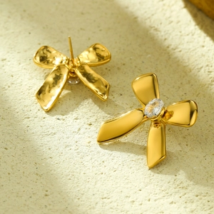 Vista macro detallada de los pendientes de lazo dorados con piedras ovales brillantes
