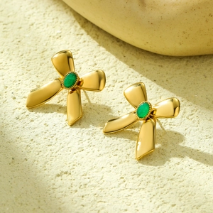 Nahaufnahme der Schleifen-Ohrstecker aus 18K Gold mit eleganten grünen Edelsteinen