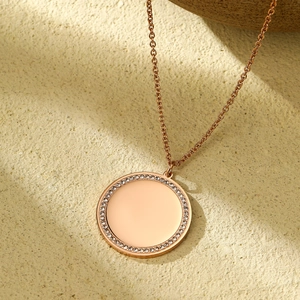 Gros plan d'un pendentif circulaire or rose avec bordure en zircon et surface miroir
