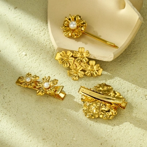 Detailed macro of gold petal hair clips with pearls and fine metallic textures