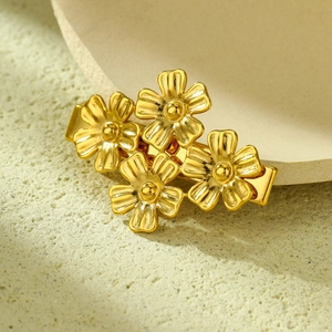 Macro shot of gold floral hair clip with pearl centers and stainless steel duckbill clamp