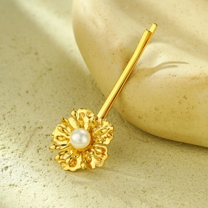 Detailed view of a gold sunflower hair clip with a white pearl on a ceramic stand
