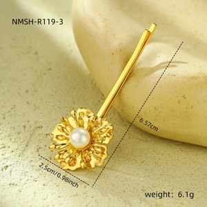 Detailed macro view of golden floral hair clip with pearl center and 6.57cm size label